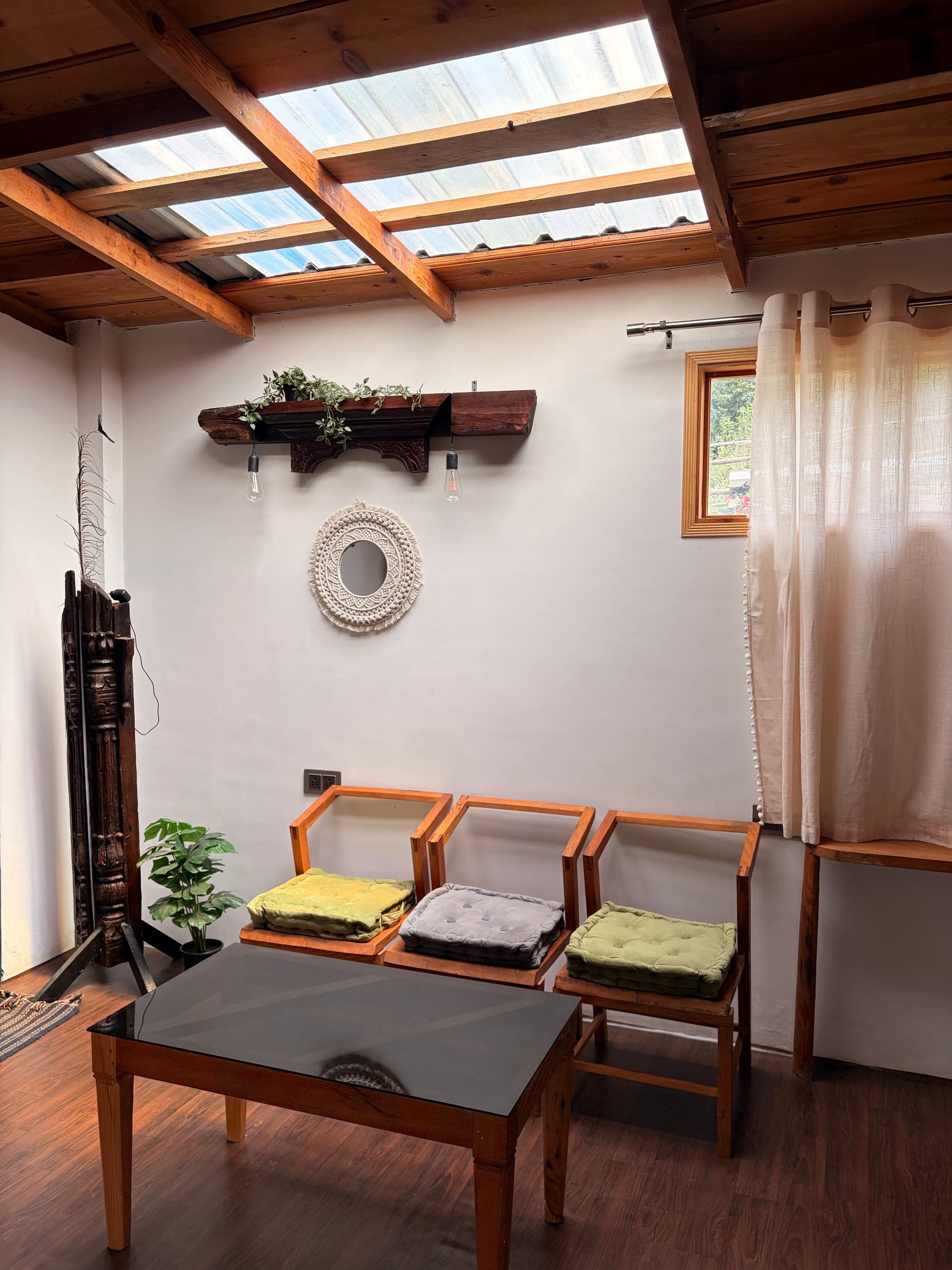 Sitting area with wooden chairs under a skylight at The Vintage Kumaon
